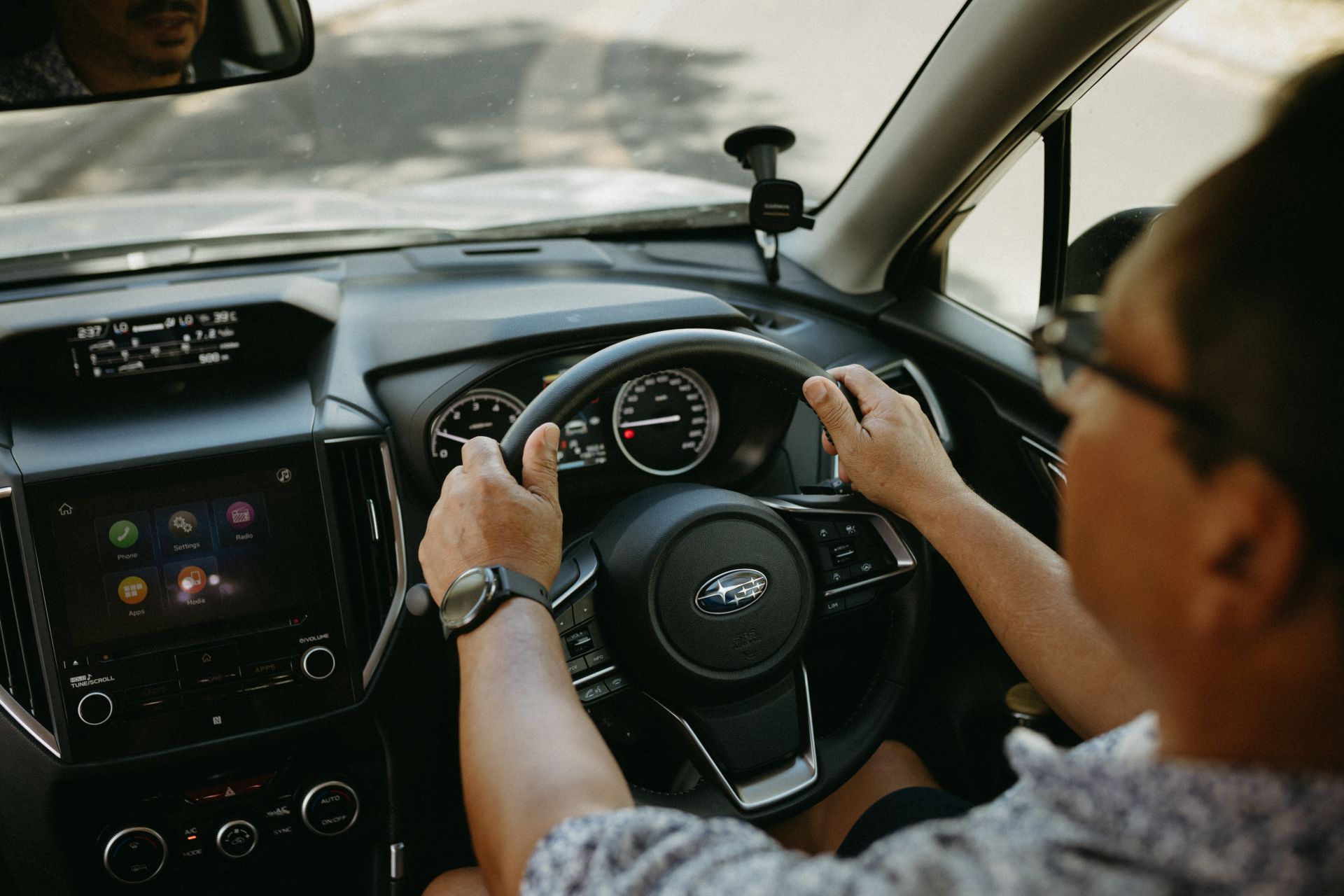 Image shows over the shoulder view of the dashboard and steering wheel of a car. 